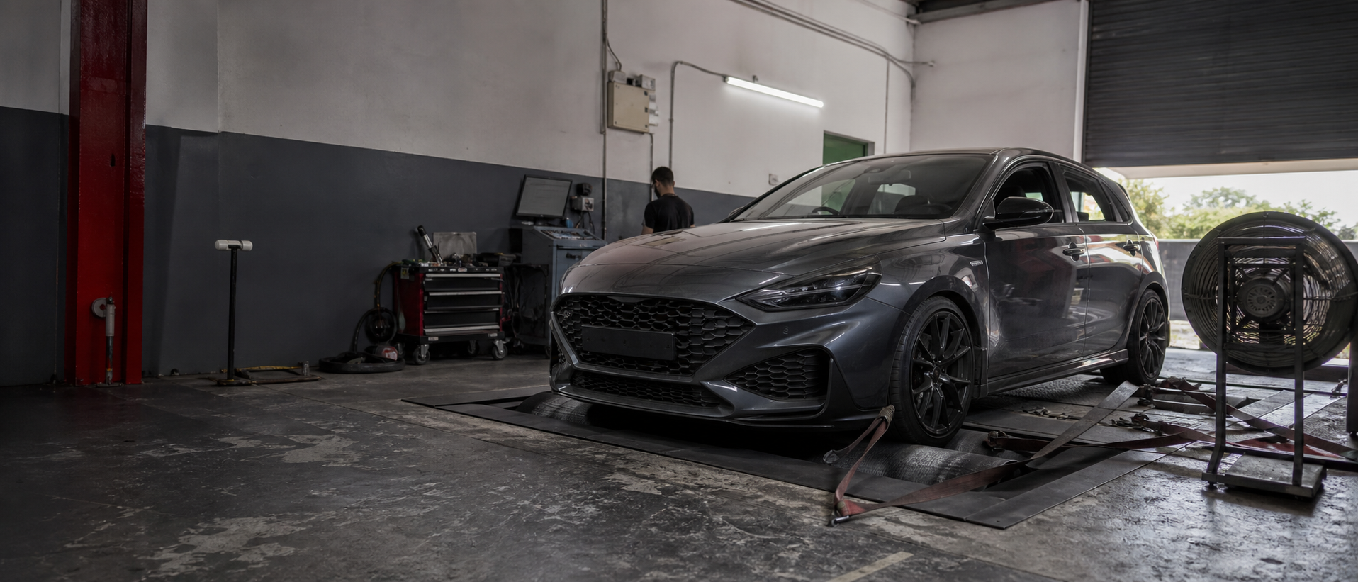 Performance hatchback undergoing dyno testing in a working calibration workshop